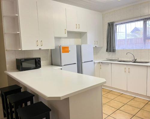 a kitchen with white cabinets and a white refrigerator at Summerstrand holiday home in Summerstrand