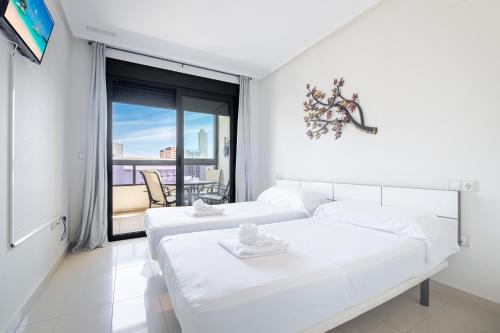 een witte slaapkamer met 2 bedden en een groot raam bij Gemelos 26 Resort Apartment 9-C Levante Beach in Benidorm