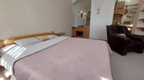 ein Schlafzimmer mit einem großen Bett und einem Ledersessel in der Unterkunft Stendera 5 in Liepāja
