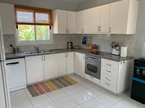 a white kitchen with white cabinets and a sink at Holiday Home Emba in Emba