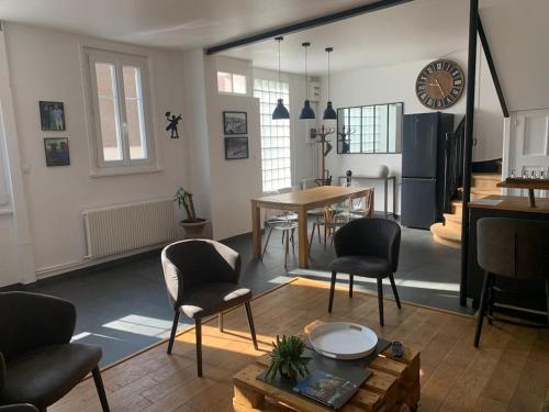 - un salon avec une table, des chaises et une horloge dans l'établissement Chrysalide au cœur du Touquet., à Le Touquet-Paris-Plage