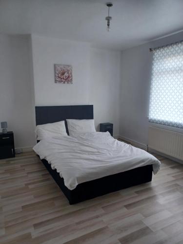 een slaapkamer met een groot bed met witte lakens bij Newcastle Home in Saint Peters