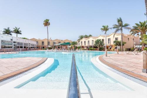 una piscina en un complejo con palmeras y edificios en Sweet Holidays, en Maspalomas