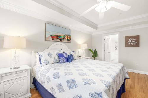 a white bedroom with a bed and a ceiling fan at Brass Rail #105 in Tybee Island