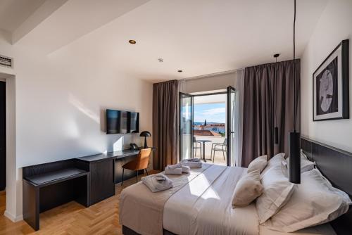 a bedroom with a bed and a desk and a window at Miramare Hotel in Zadar