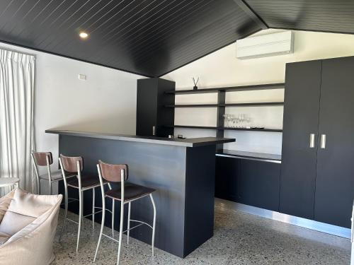 a kitchen with a black counter and stools at Guest House with a Stunning View in Frankton Wharf