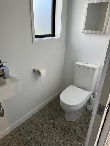 a white bathroom with a toilet and a mirror at Guest House with a Stunning View in Frankton Wharf
