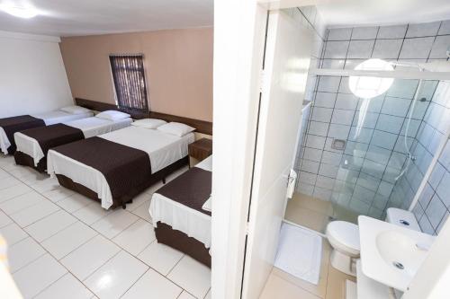 a hotel room with two beds and a shower at A1 hotel in Foz do Iguaçu