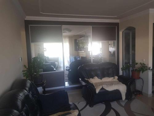 a living room with black leather chairs and a mirror at Elaktra Apartman in Szolnok