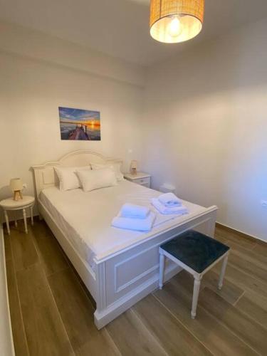 una camera con letto bianco e sgabello blu di Sea Through Apartment Anavissos ad Anávissos