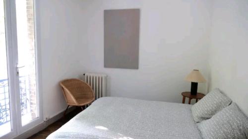 a bedroom with a bed and a chair and a window at Comme une petite maison en ville in Montrouge