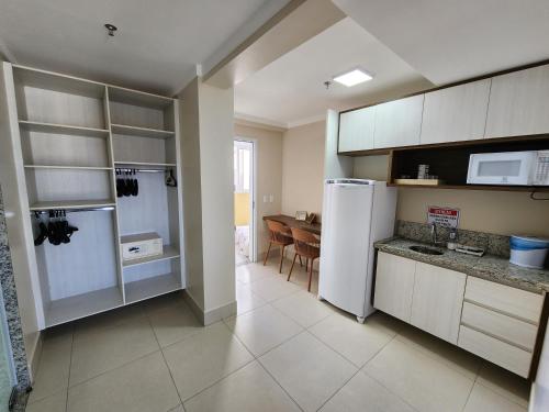 a kitchen with a white refrigerator and a table at Spazzio diRoma - Apartamentos JN in Caldas Novas