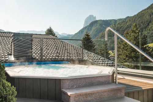 una bañera de hidromasaje en un balcón con montañas al fondo en Boutique Hotel Planlim, en Ortisei