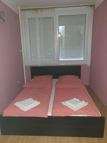 a bedroom with two beds with red sheets and a window at Goldapartman Salgótarján in Salgótarján