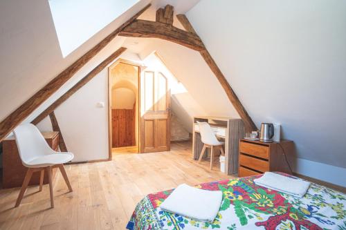 a attic room with a bed and two chairs at Chambres d hôtes du Moulin de Boiscorde in Rémalard en Perche