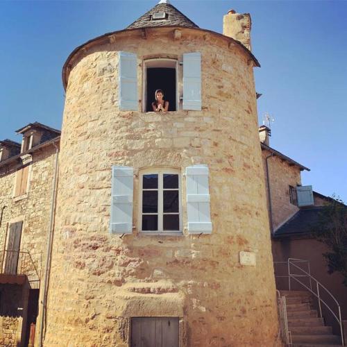 une femme regardant par la fenêtre d'une tour dans l'établissement Charming House in Gorgeous, Quiet Village in the Aveyron countryside, à Vimenet
