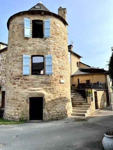 un vieux bâtiment en briques avec des fenêtres et des escaliers bleus dans l'établissement Charming House in Gorgeous, Quiet Village in the Aveyron countryside, à Vimenet
