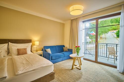 a bedroom with a bed and a blue chair and a window at Wellness Hotel Queens in Mariánské Lázně