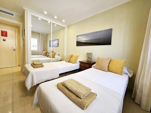 a hotel room with two beds and a mirror at Apartamento NEPTUNO - Primera Línea de Playa in El Campello