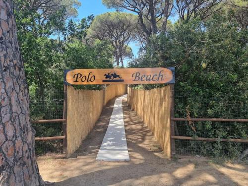 a wooden bridge with a sign that reads polo beach at Casa Bortoli in Castiglione della Pescaia