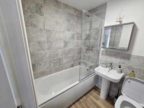 y baño con bañera de ducha y lavamanos. en Oakmere Apartments en Chinley
