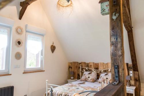 1 dormitorio con cama de madera en el ático en Le Clos du Val à Loup en Bénarville