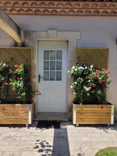 eine Haustür eines Hauses mit zwei Blumen in der Unterkunft Petit pavillon cosy avec extérieur in Mèze