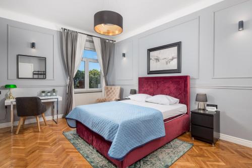a bedroom with a bed with a red headboard and a desk at apartment Tiziano-Belveder with private garage in Rijeka