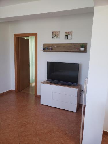a living room with a flat screen tv on a white cabinet at Apartmani Čiklić in Dobropoljana