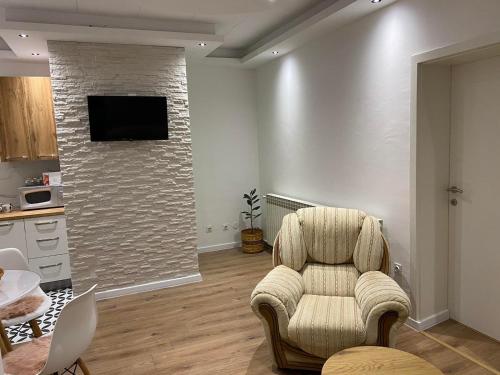 a living room with a chair and a tv on a wall at Apartman UNA-Plandište in Bihać