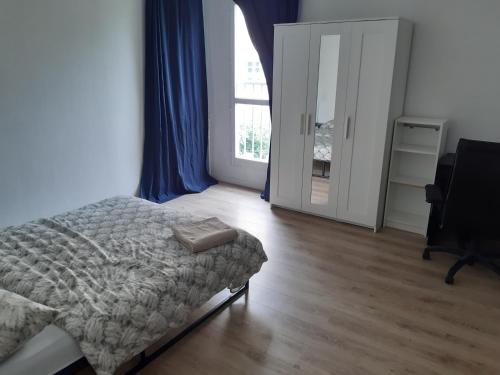 a bedroom with a bed and a desk and a window at Bel appartement avec Terasse Proche Gare in Cergy