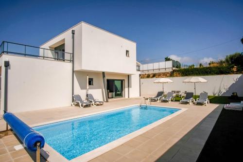 a swimming pool in front of a house at Villa Serra Mar in São Martinho do Porto