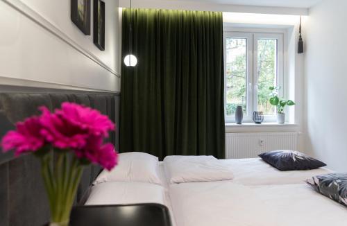 a bedroom with a white bed and a vase of pink flowers at FLATMORE Apartament Akacjowa 17m1B in Zielona Góra