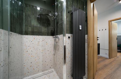 a bathroom with a shower with green and white tiles at FLATMORE Apartament Akacjowa 17m1B in Zielona Góra