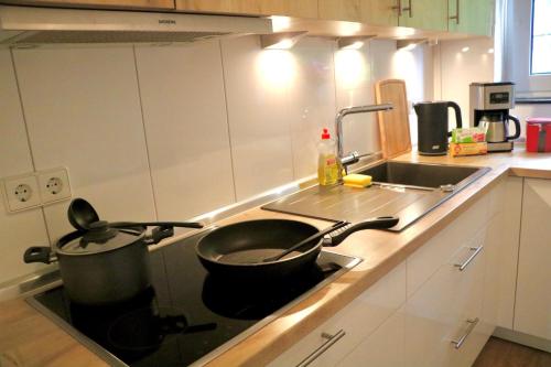 a frying pan sitting on a stove in a kitchen at EcoCube 142 - Balkon, 3Zimmer, Schlafsofa, Waschmaschine, Backofen, 6Pers in Meppen