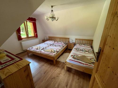 a bedroom with two beds and a chandelier at Chata na Zbojskej in Pohronská Polhora