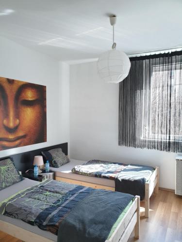 a bedroom with two beds and a painting of a face at Green Apartman Salgótarján in Salgótarján