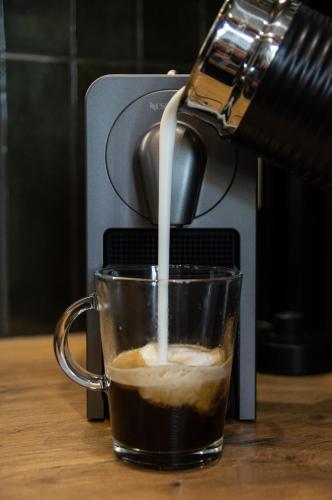 a person pouring milk into a cup of coffee at FLATMORE Apartament Akacjowa 17m1B in Zielona Góra