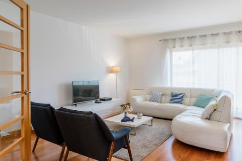een woonkamer met een witte bank en een tv bij Garden Mills Apartment in Lissabon