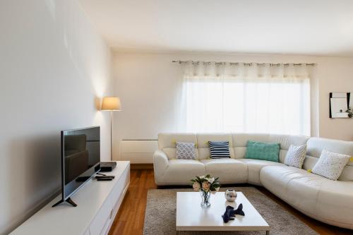 a living room with a white couch and a tv at Garden Mills Apartment in Lisbon