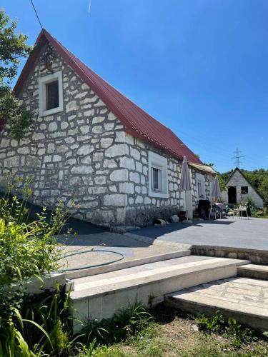 a stone building with a red roof and a patio at Odmaralište Petnjica in Šavnik