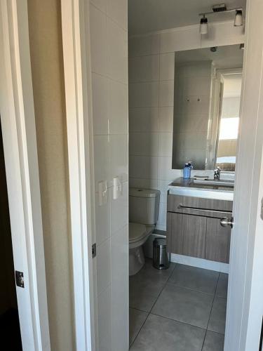 a bathroom with a toilet and a sink and a mirror at Edificio Concepto in Calama