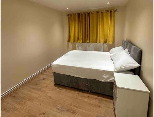 um quarto com uma cama e uma cortina amarela em 2BR Flat near Central Southall em Southall