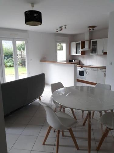 - une cuisine avec une table et des chaises dans la chambre dans l'établissement Appartement au RDC avec jardin clos, au calme., à Saint-Aubin-du-Cormier