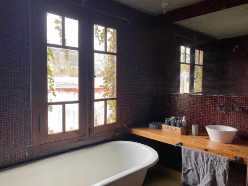 a bathroom with a tub and a sink and windows at Casa Almendra in Rosario