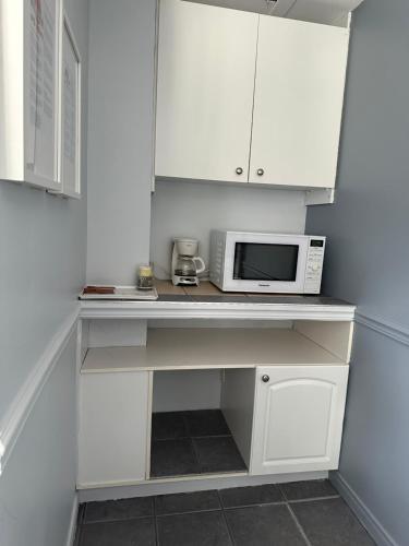 a kitchen with white cabinets and a microwave and a counter at Motel Le Refuge in Sherbrooke