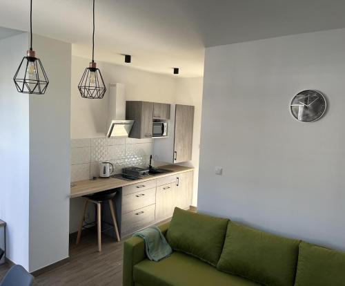 uma sala de estar com um sofá verde e uma cozinha em Apartamenty Pod Jodłami em Sarbinowo