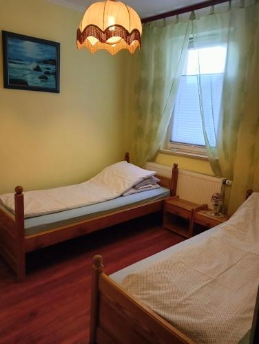 a bedroom with two beds and a window and a chandelier at Mieszkanie nad Szeszupą 16-406 Rutka-Tartak ul, 3 go Maja 1 in Rutka Tartak