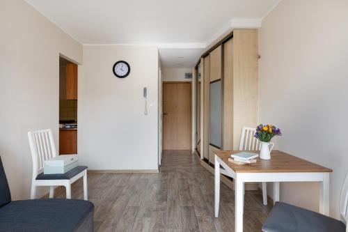 a living room with a table and chairs and a clock at INITIUM rooms - Apartament - Tysiąclecia 23B in Gdańsk