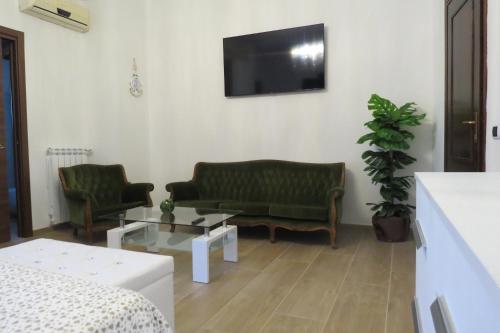 a living room with two green couches and a tv at DA LELLO - Bed & Relax in Torrecuso